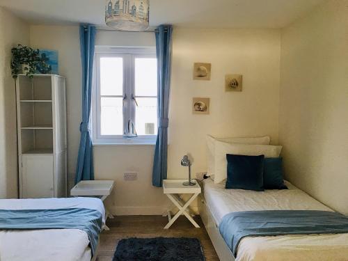 a small bedroom with two beds and a window at Curlew in Brightlingsea