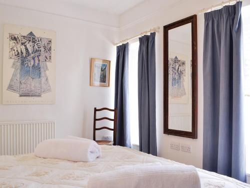 a bedroom with a bed with blue curtains and a mirror at The Mill House, The Square in Talgarth