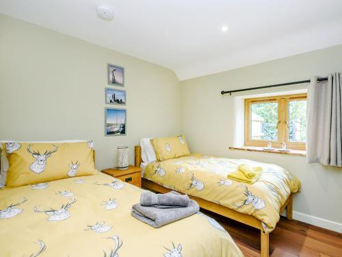 1 dormitorio con 2 camas y ventana en Stackyard Cottage, en Felmingham