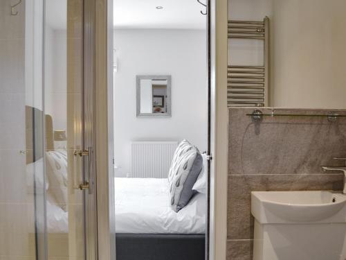a bathroom with a bed and a sink and a mirror at Regent Cottage in Beverley