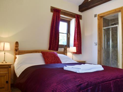 a bedroom with a bed with red curtains and a window at Cider Press Barn - Uk12379 in Lydney