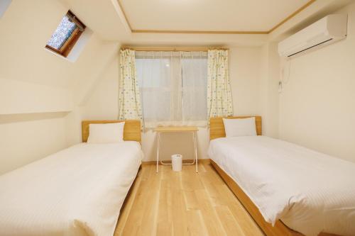 two beds in a small room with a window at Hotaku House Akihabara #HO1 in Tokyo