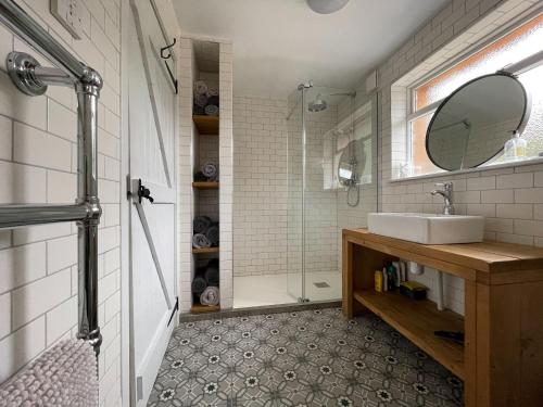 a bathroom with a sink and a shower with a mirror at Lower Hilton Cottage in Culrain