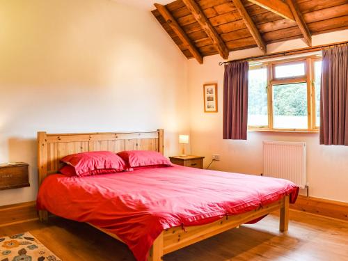a bedroom with a bed with red sheets and a window at The Long Barn in Little Baddow