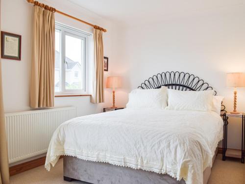 1 dormitorio con 1 cama blanca y ventana en Trondra House, en Ferryside