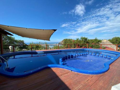 uma piscina azul num deque com um guarda-sol em Siete Piedras Beachfront Village em Troncones