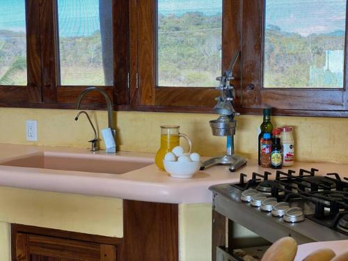 a kitchen with a sink and a stove and windows at Siete Piedras Beachfront Village in Troncones