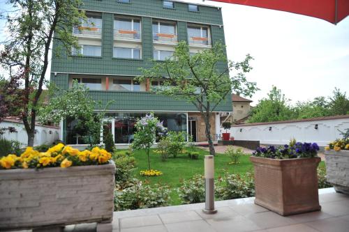 a building with flowers in front of a yard at Hotel Jasmine in Braşov