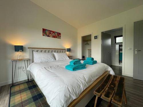 sypialnia z dużym białym łóżkiem z niebieskimi ręcznikami w obiekcie Willow Lodge w mieście Muir of Ord