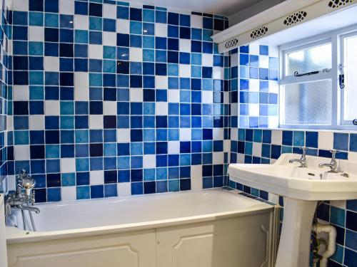 a blue and white tiled bathroom with a tub and sink at Plum Tree Cottage in Trent