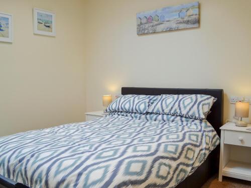 a bedroom with a bed with a blue and white comforter at The Hideaway in Sheringham