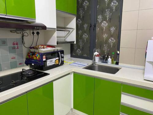 a kitchen with green and white cabinets and a sink at The Makcik's @UNIV360 Serdang in Seri Kembangan