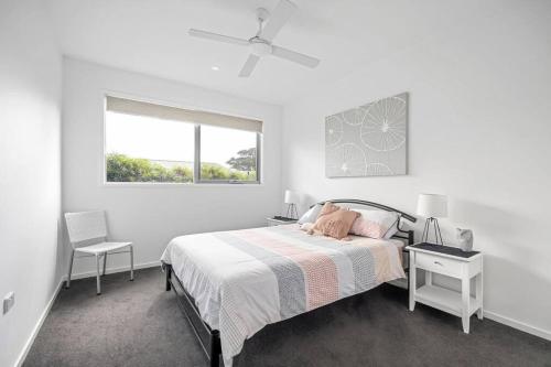 a white bedroom with a bed and a window at Lighthouse Views, McCrae in McCrae
