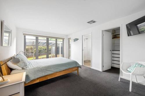 a white bedroom with a bed and a window at Lighthouse Views, McCrae in McCrae