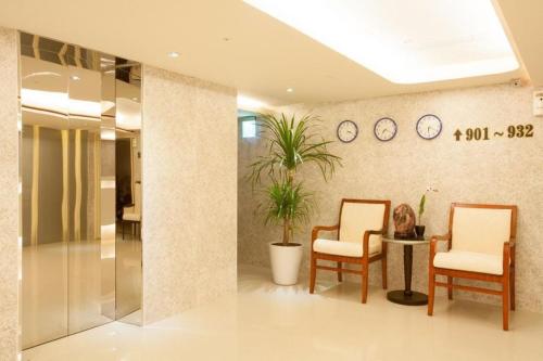 um átrio com duas cadeiras, uma mesa e relógios em Guide Hotel Taoyuan Fuxing em Taoyuan
