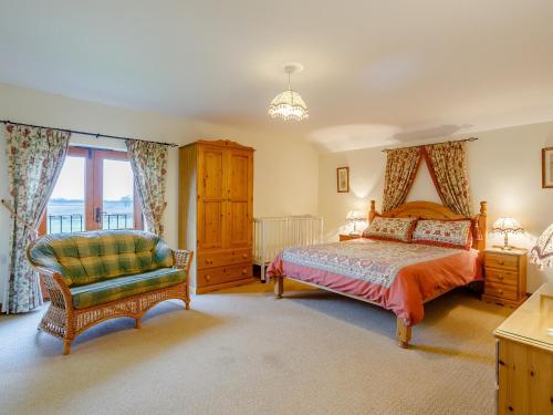 um quarto com uma cama e uma cadeira em Pantiles Barn - E3866 em Runcton Holme
