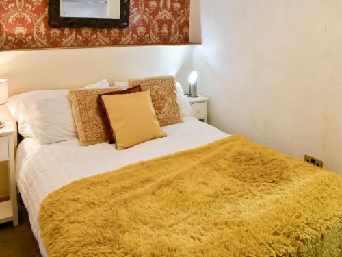 a bedroom with a bed with a yellow blanket on it at The Archway in Newnham