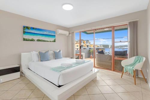 a white bedroom with a bed and a balcony at Jervis Bay Vista in Huskisson