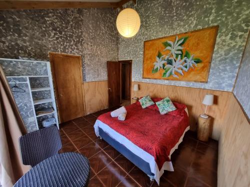 a bedroom with a red bed and two chairs at Hostal Vieroto in Hanga Roa