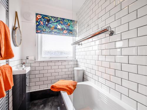 a white tiled bathroom with a tub and a window at Grayson Avenue in Pakefield