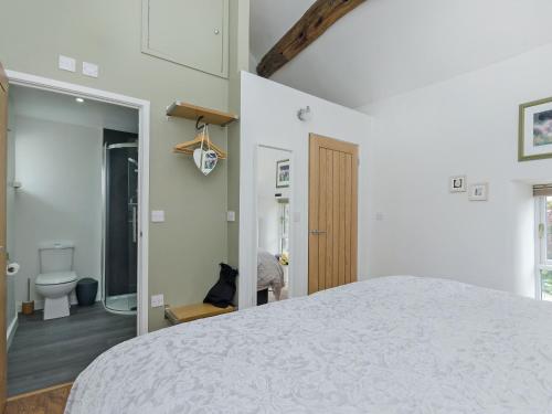 a bedroom with a white bed and a bathroom at Baileys Barn in Bonsall