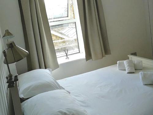 a white bed in a bedroom with a window at Oake Cottage in Warkworth