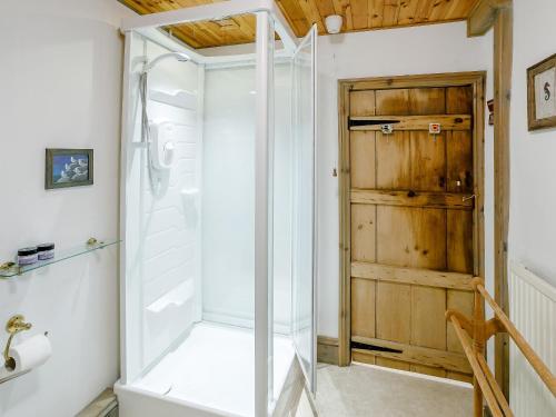 a glass shower in a bathroom with a wooden door at The Hayloft in Glossop