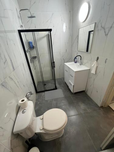 a white bathroom with a toilet and a sink at Surfers Paradise Beach House in Herzelia 