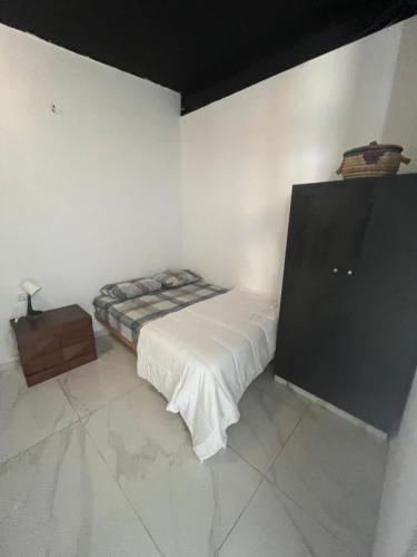 a white room with a bed and a television at Surfers Paradise Beach House in Herzelia 