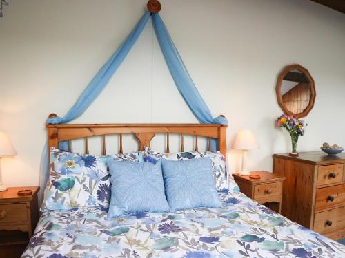1 dormitorio con cama con dosel azul y almohadas azules en Woodland View - Hmr, en Combe Martin