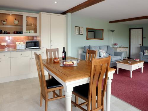 cocina y sala de estar con mesa de madera y sillas en Woodland View - Hmr, en Combe Martin