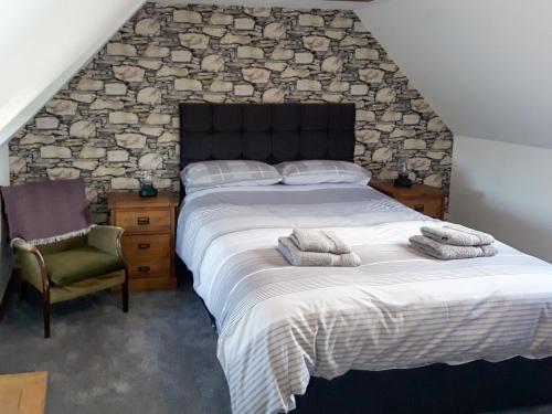 a bedroom with a large bed with a stone wall at Macrury Cottage in Paible