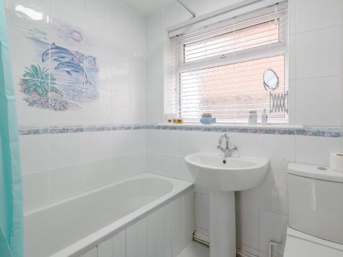 a white bathroom with a sink and a bath tub at Anchorage in Sutton on Sea