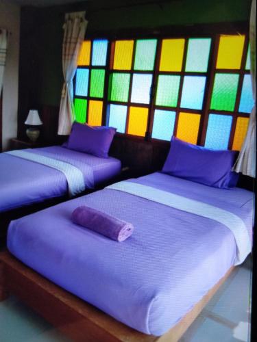 two beds in a room with stained glass windows at เชียงคานบุรี in Chiang Khan