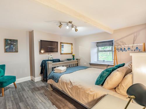 1 dormitorio con 1 cama y TV en la pared en Burnside Cottage en Bardon Mill