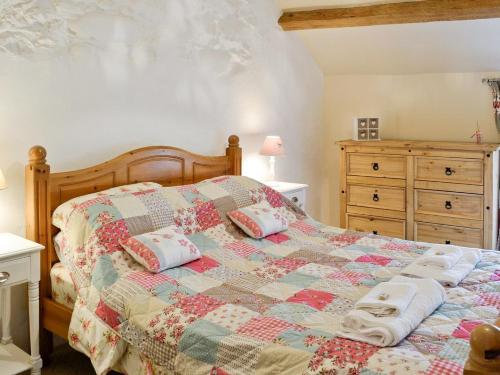 a bedroom with a bed with a quilt on it at Clogwyn Bach in Trevor