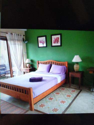 - une chambre avec un grand lit et un mur vert dans l'établissement เชียงคานบุรี, à Chiang Khan