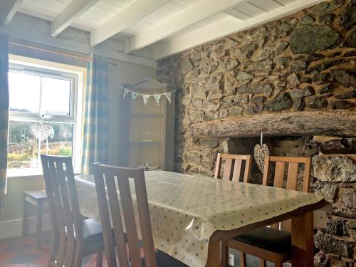 a dining room with a table and chairs and a stone wall at Stephens Cottage in Llangwm