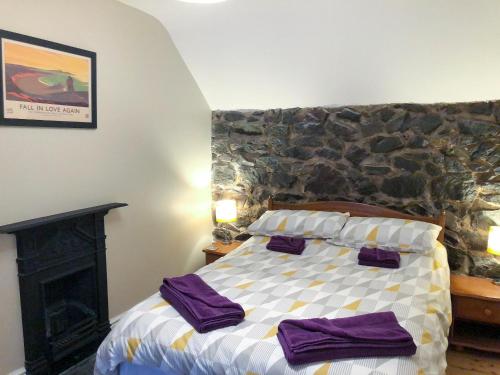 a bedroom with a bed and a stone wall at Stephens Cottage in Llangwm
