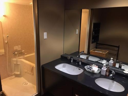 a bathroom with two sinks and a large mirror at Oyado Kinkiyu Annex SUIKAZURA in Teshikaga