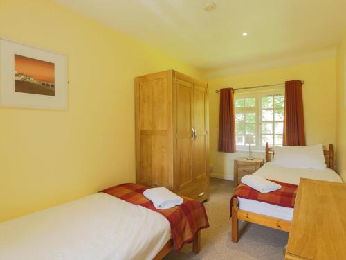 a bedroom with two beds and a cabinet at Drovers in Lanteglos