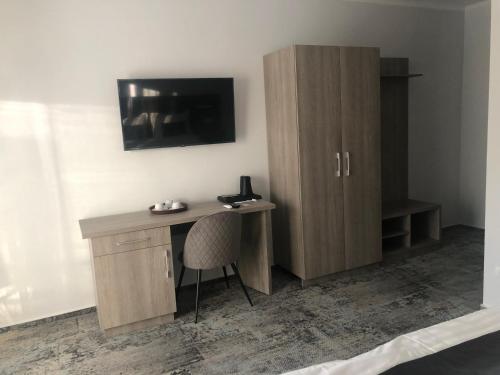 a desk with a cabinet and a television on a wall at Sub Cetate in Râşnov
