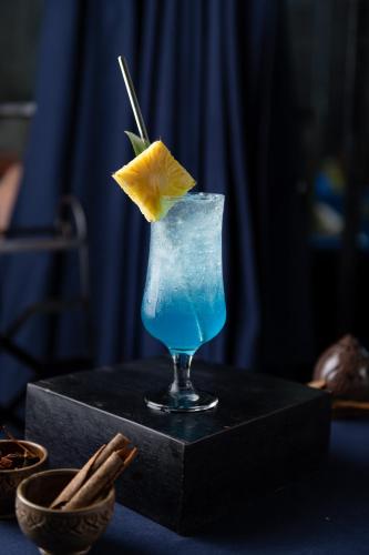 a blue drink with a yellow flower in a glass at Bayon Modern Residence in Siem Reap