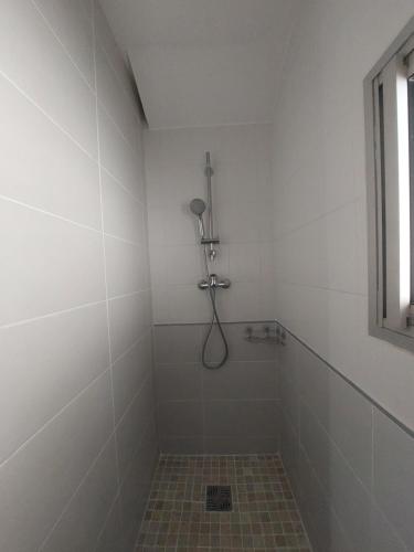 a white bathroom with a shower with a tile floor at La Cas'Aline in La Saline les Bains