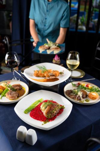 a table with plates of food and glasses of wine at Bayon Modern Residence in Siem Reap