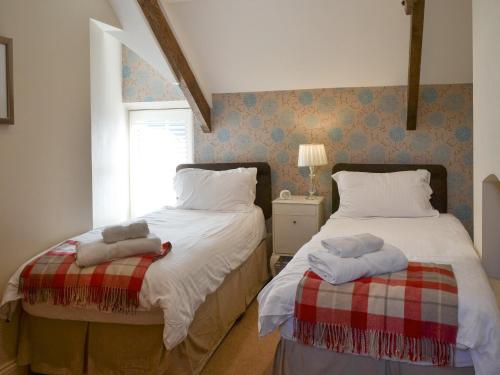 a bedroom with two beds and a window at Wagtail Cottage in Lesbury