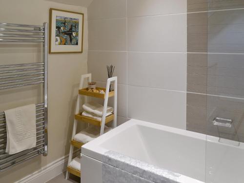 a white bathroom with a tub and a shower at Wagtail Cottage in Lesbury