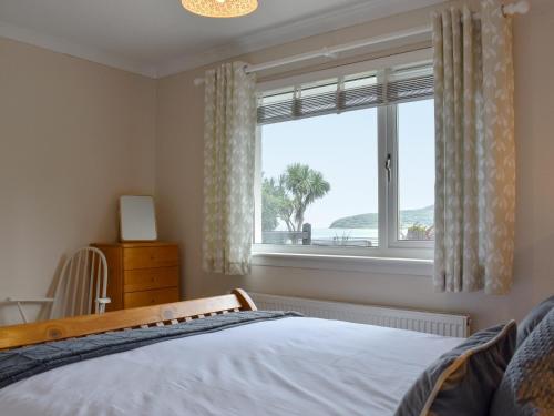 a bedroom with a bed and a large window at Anchorage Cottage in Lamlash