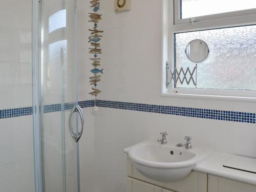 ein weißes Bad mit einem Waschbecken und einer Dusche in der Unterkunft Coles Retreat in Anderby