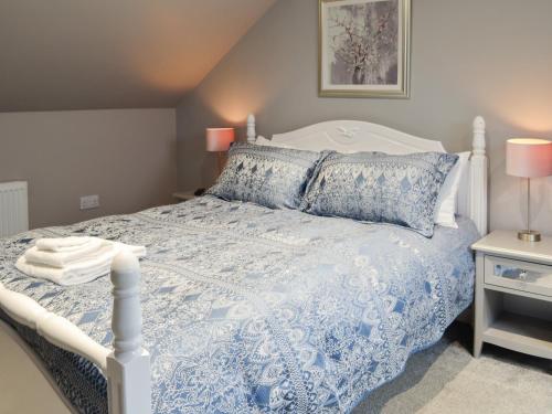 een slaapkamer met een blauw en wit bed met kussens bij Donallan in Palnure
